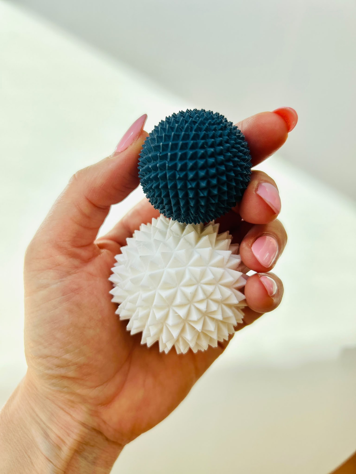 Zwei Spike Balls — grau und weiß — in der Hand