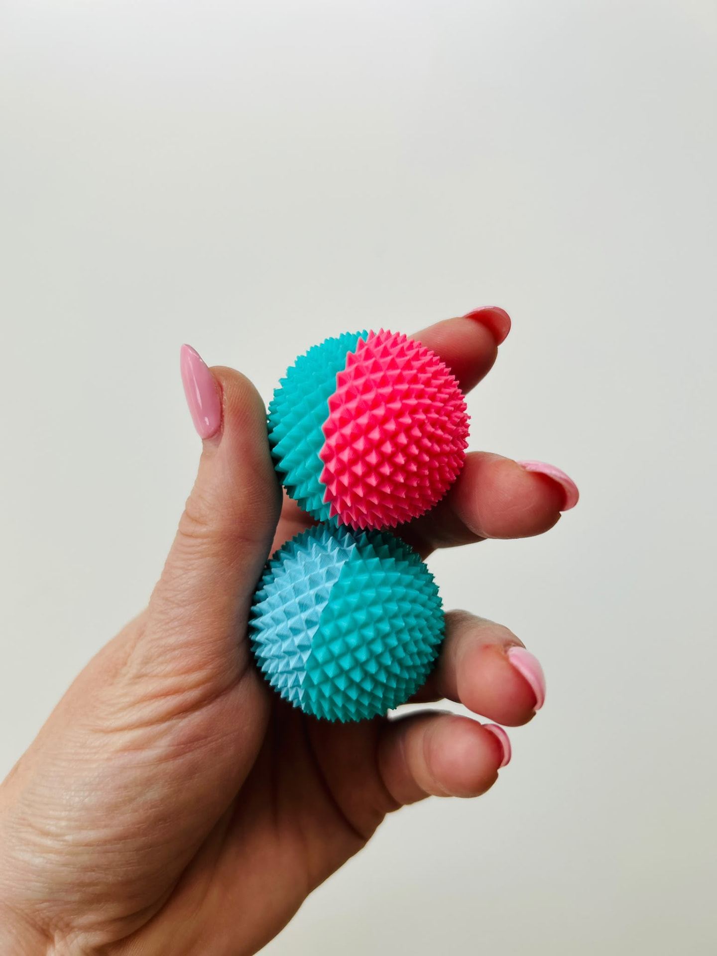 Zwei zweifarbige Spike Balls in der Hand